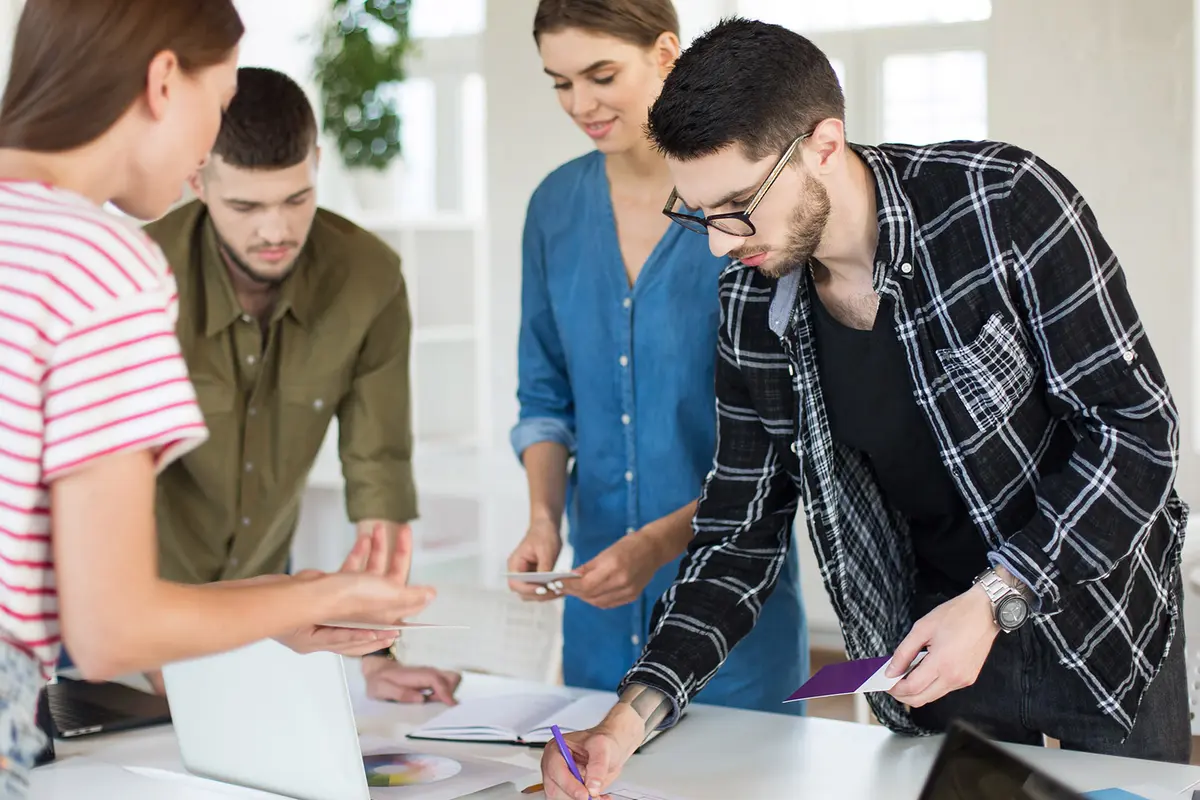 banner__0000s_0004_thoughtful-man-shirt-eyeglasses-working-with-sketches-while-spending-time-with-colleagues-work-group-